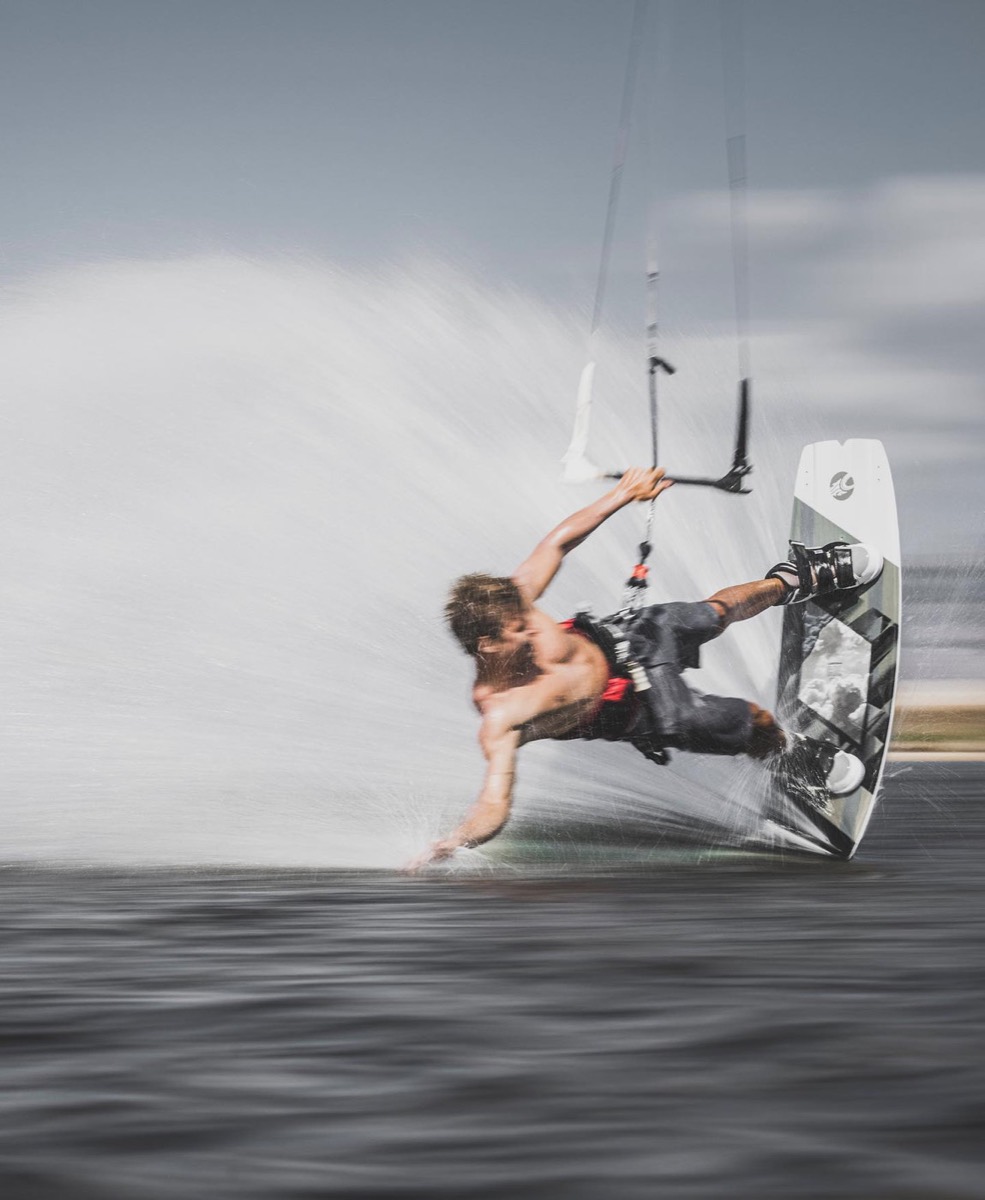 Lucas carving on a kiteboard, throwing spray