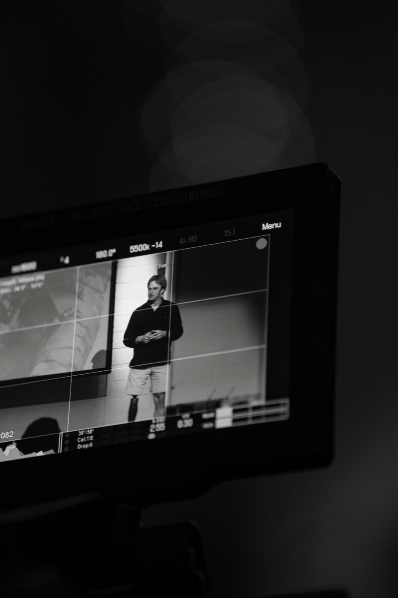 A camera monitor framing Lucas on stage during his keynote